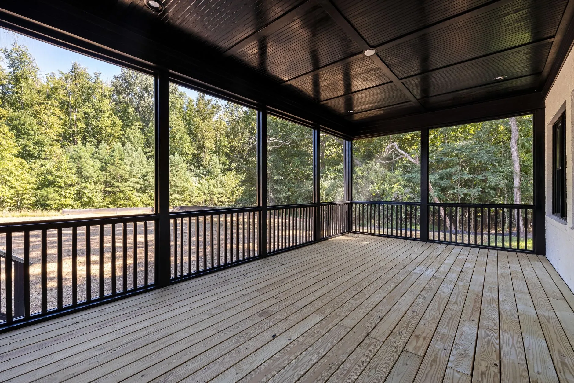 Covered pressure-treated deck with dark ceiling and wood decking, built in Burnaby